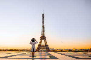 A lady standing in front of the Eiffel tower at sunset