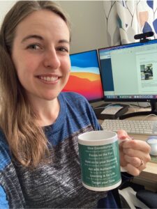 Issy sitting at her desk holding the Dialogue mug