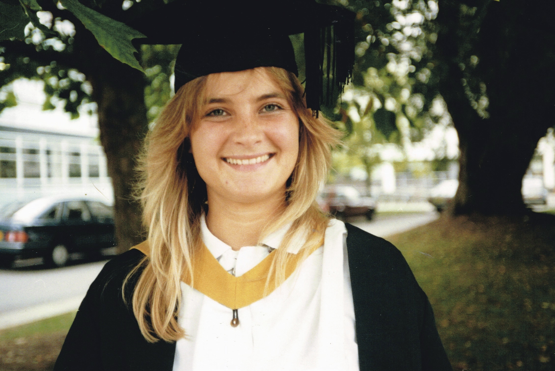 Nicola on her graduation day, in her gown and hat, smiling at the camera