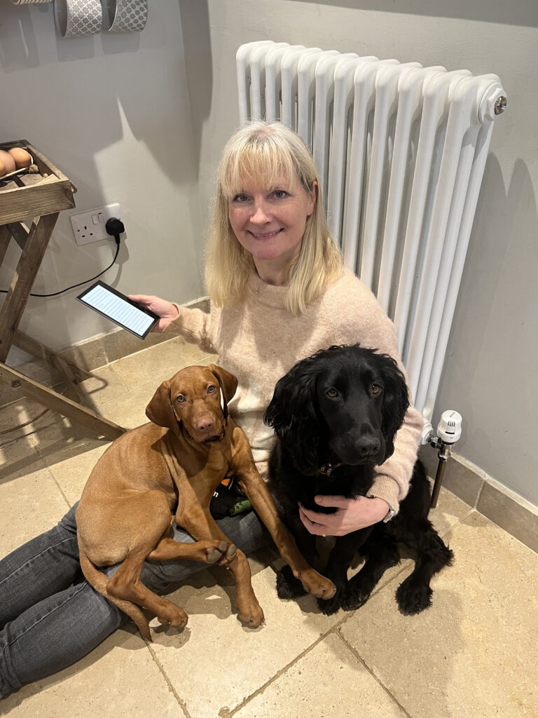 Nicola, our CEO, sitting with her two dogs on the floor while reading her kindle